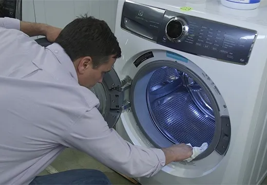 Мужчина вытирает стиральную машину
