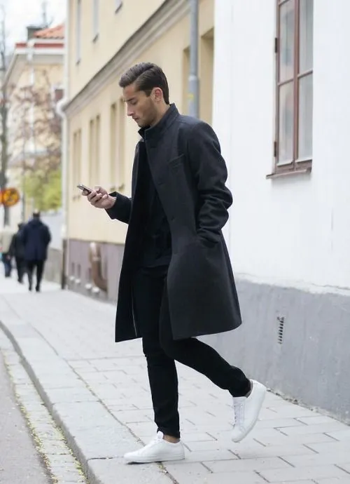 Мужчина в белых кроссовках и черном пальто