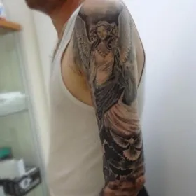 Татуировка ангела и голубей на руке мужчины